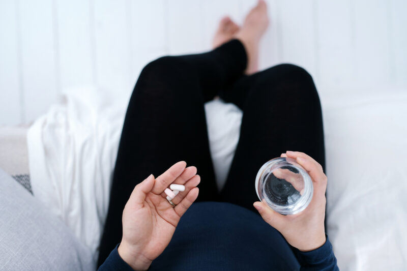 Woman preparing to take a vitamin D supplement with a glass of water